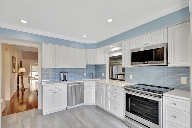 kitchen with appliances with stainless steel finishes, white cabinetry, crown molding, and sink