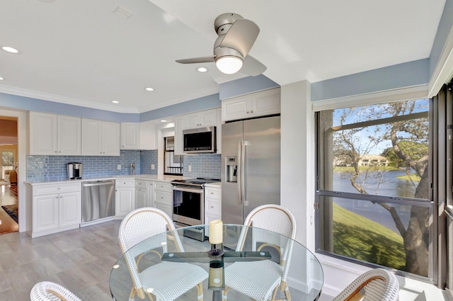 kitchen featuring decorative backsplash, white cabinetry, crown molding, and appliances with stainless steel finishes