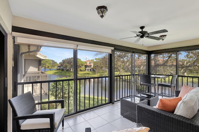 sunroom featuring ceiling fan and a water view