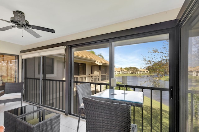 sunroom featuring ceiling fan and a water view