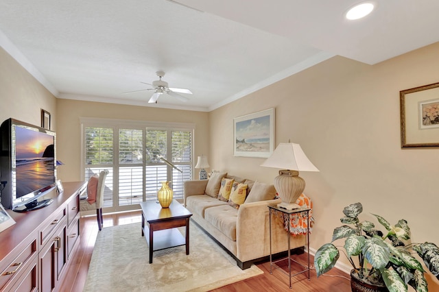 living room with light hardwood / wood-style flooring, ceiling fan, and crown molding