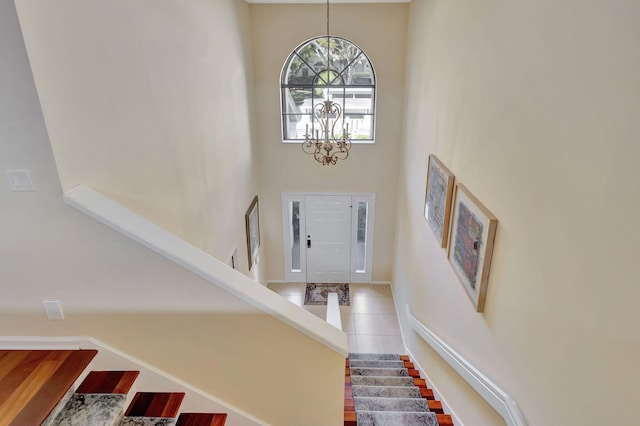 tiled foyer entrance with a towering ceiling and a notable chandelier