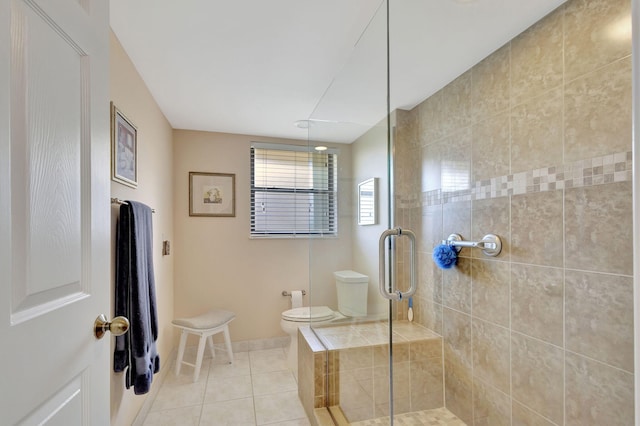 bathroom with tile patterned floors, toilet, and a tile shower