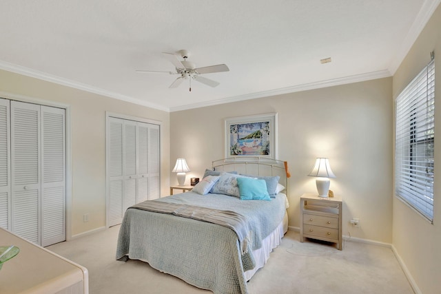 carpeted bedroom featuring multiple closets, ceiling fan, and ornamental molding