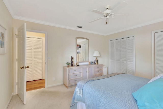 bedroom featuring light carpet, two closets, ceiling fan, and ornamental molding