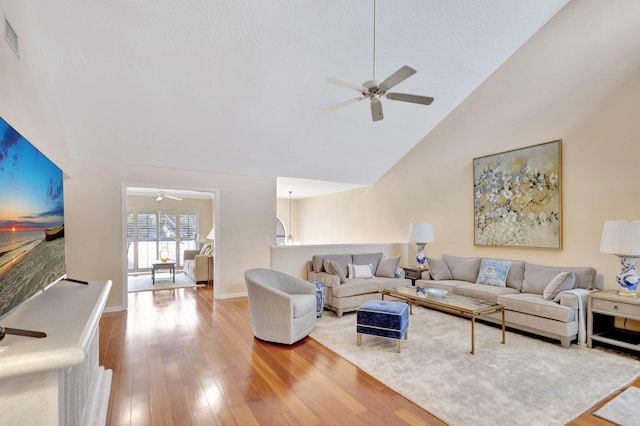 living room with ceiling fan, wood-type flooring, and high vaulted ceiling