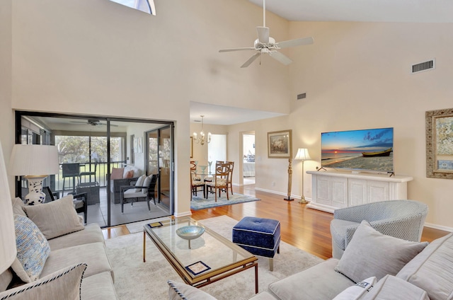 living room featuring ceiling fan with notable chandelier, light hardwood / wood-style floors, and high vaulted ceiling