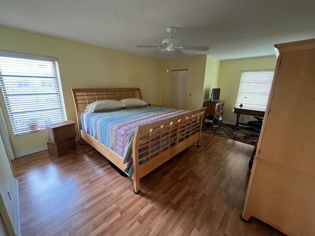 bedroom with a textured ceiling, wood-type flooring, ceiling fan, and a closet