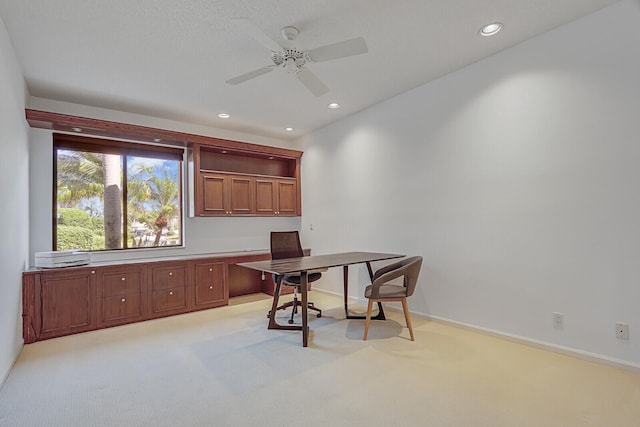 carpeted office with built in desk and ceiling fan