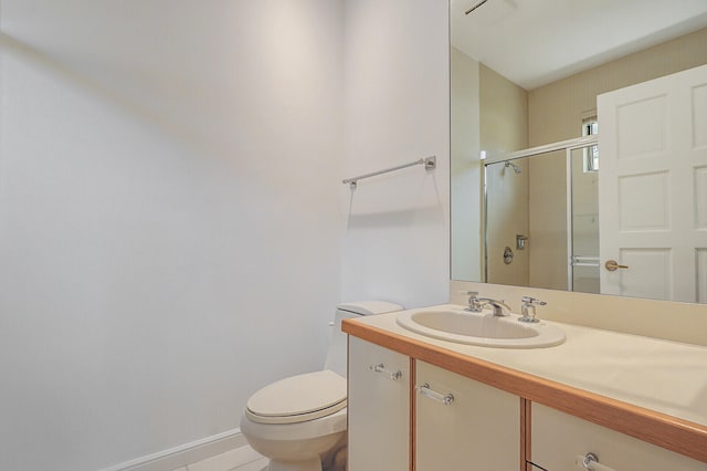 bathroom featuring toilet, vanity, and a shower with shower door