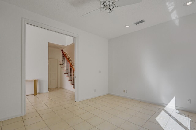 tiled empty room featuring ceiling fan and a textured ceiling