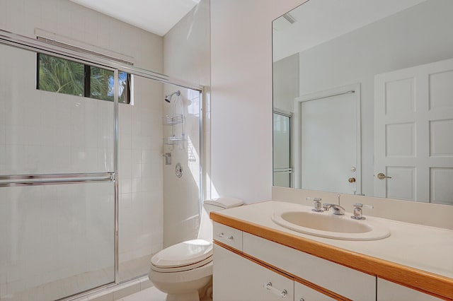 bathroom with toilet, vanity, and a shower with door