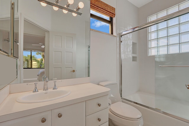 full bathroom featuring ceiling fan, bath / shower combo with glass door, vanity, and toilet