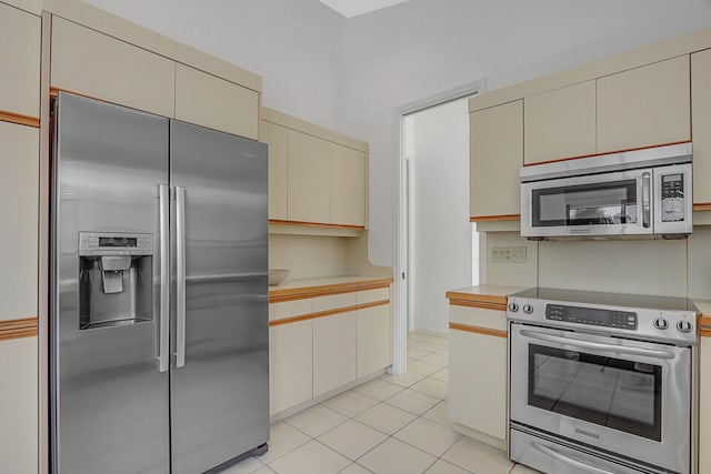 kitchen featuring appliances with stainless steel finishes, cream cabinets, and light tile patterned floors