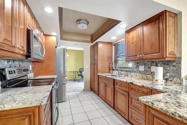 kitchen featuring light stone countertops, sink, stainless steel appliances, backsplash, and a tray ceiling