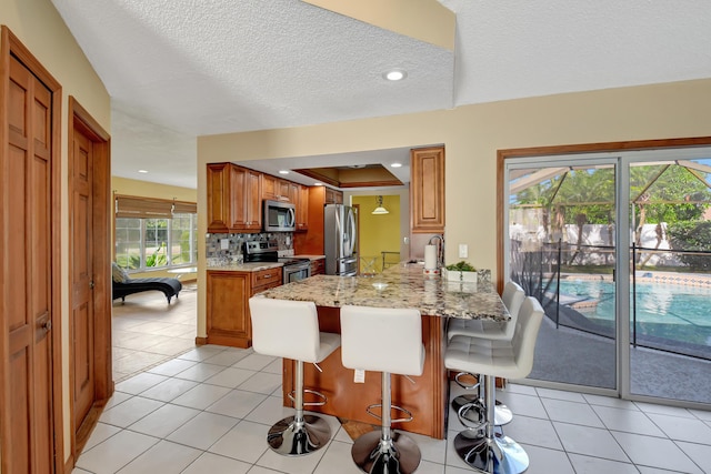 kitchen featuring a breakfast bar, stainless steel appliances, kitchen peninsula, and light tile patterned flooring