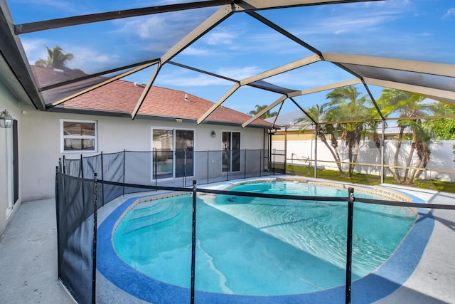 view of swimming pool featuring glass enclosure and a patio