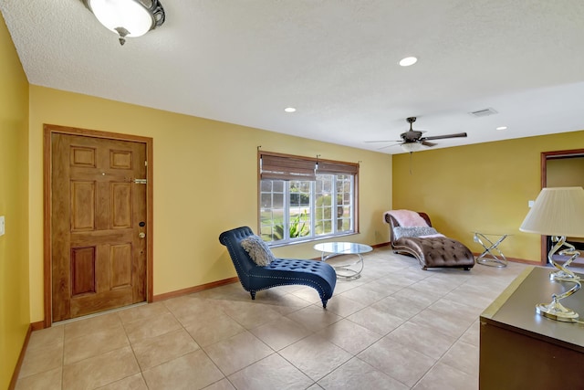 living area featuring light tile patterned floors, a textured ceiling, and ceiling fan