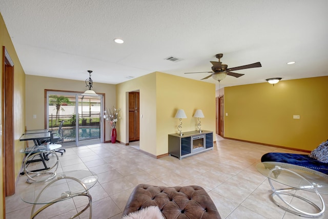 tiled living room featuring ceiling fan and a textured ceiling