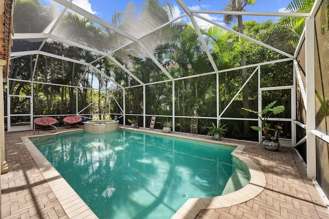 view of pool with a lanai, a patio area, and an in ground hot tub