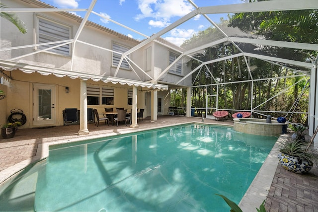 view of pool with an in ground hot tub, a patio area, and glass enclosure