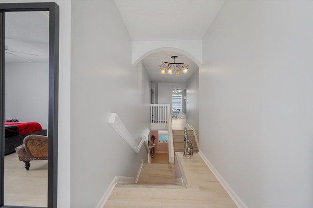 staircase featuring wood-type flooring, a chandelier, and a textured ceiling