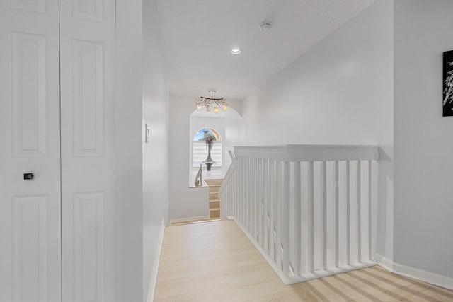 corridor featuring light hardwood / wood-style flooring and a notable chandelier