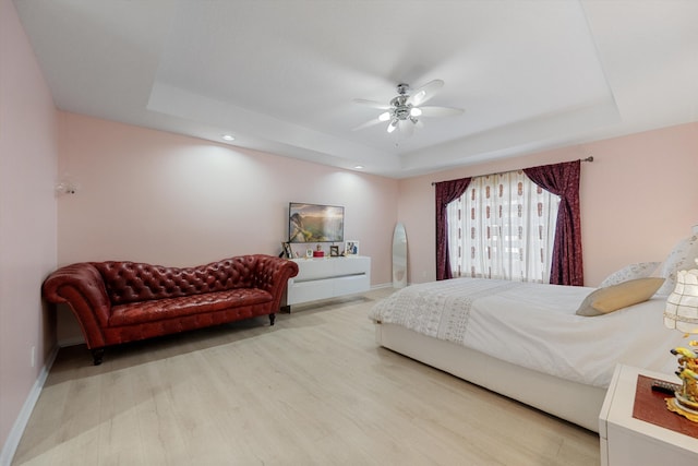 bedroom featuring ceiling fan, wood-type flooring, and a tray ceiling