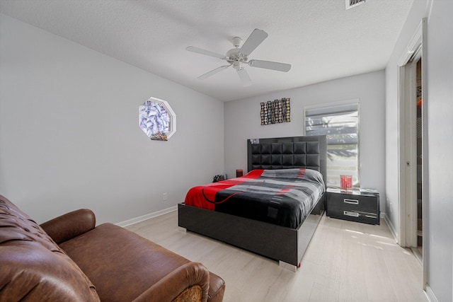 bedroom featuring ceiling fan, a textured ceiling, and light wood-type flooring