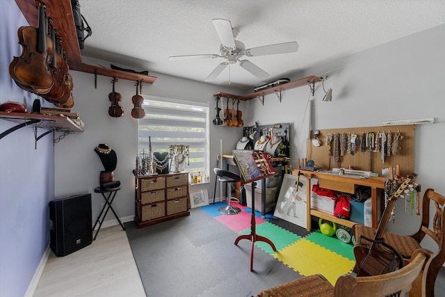 recreation room with ceiling fan, a workshop area, and a textured ceiling