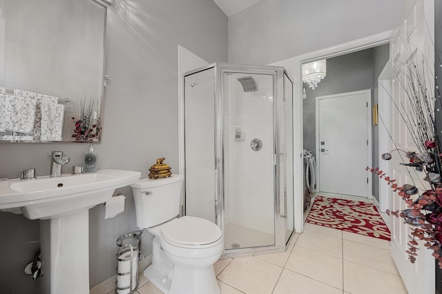 bathroom featuring washer and clothes dryer, an enclosed shower, tile patterned floors, and toilet