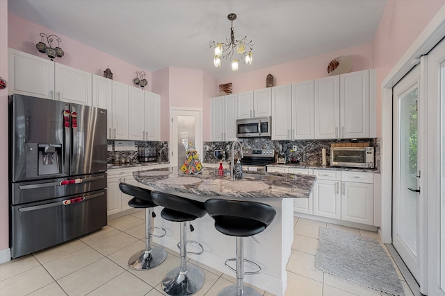 kitchen featuring white cabinets, appliances with stainless steel finishes, sink, and dark stone counters