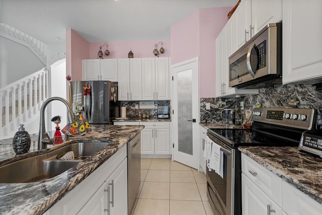 kitchen featuring appliances with stainless steel finishes, sink, dark stone countertops, and white cabinets