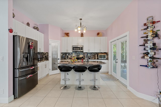 kitchen featuring a kitchen bar, a center island with sink, dark stone counters, pendant lighting, and stainless steel appliances