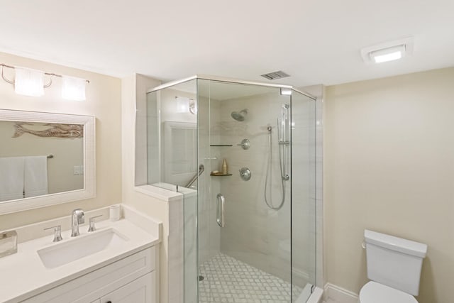 bathroom featuring a shower with shower door, vanity, and toilet