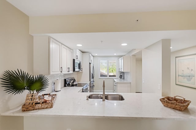 kitchen with white cabinetry, sink, appliances with stainless steel finishes, light stone countertops, and decorative backsplash