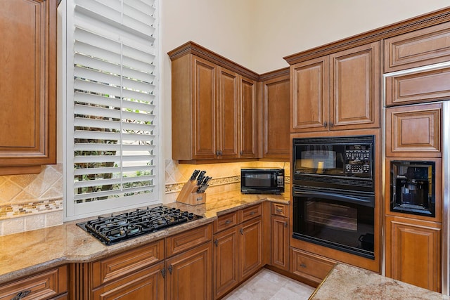 kitchen with black appliances, light stone countertops, and tasteful backsplash