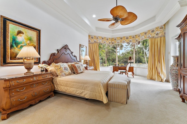 carpeted bedroom with ceiling fan, a raised ceiling, and ornamental molding