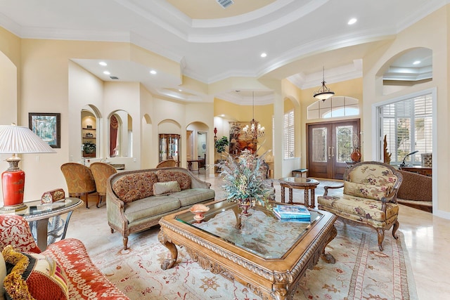 living room featuring french doors, a towering ceiling, a notable chandelier, and ornamental molding