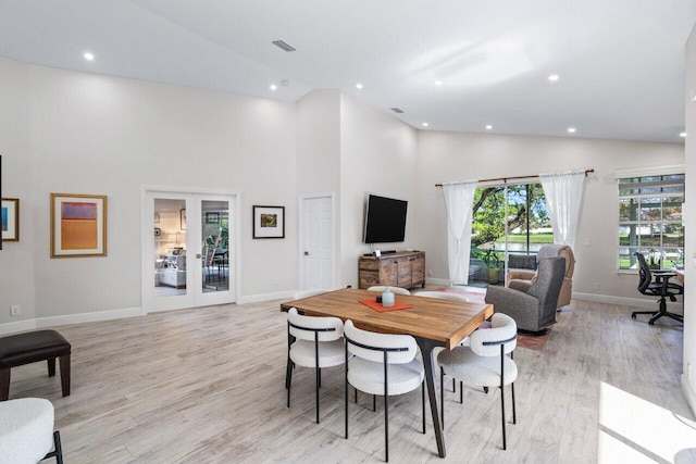 dining space with french doors, light wood-type flooring, and high vaulted ceiling