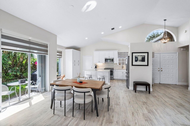 dining room featuring high vaulted ceiling, a chandelier, and light wood-type flooring