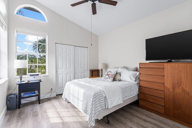 bedroom with hardwood / wood-style flooring, ceiling fan, high vaulted ceiling, and a closet