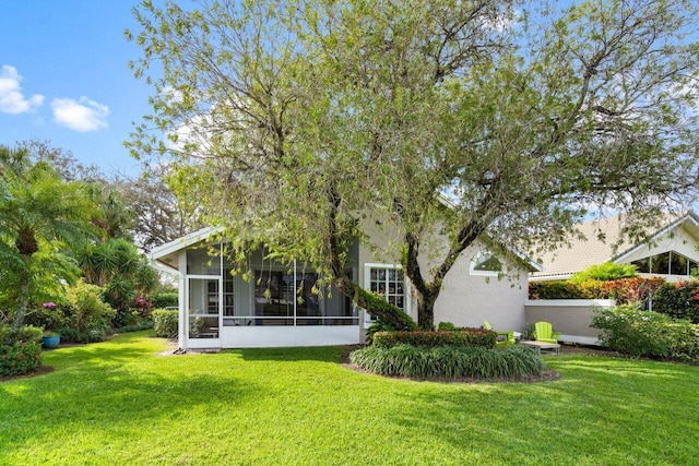 back of property featuring a sunroom and a yard