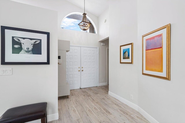 entrance foyer featuring light hardwood / wood-style flooring, high vaulted ceiling, and an inviting chandelier