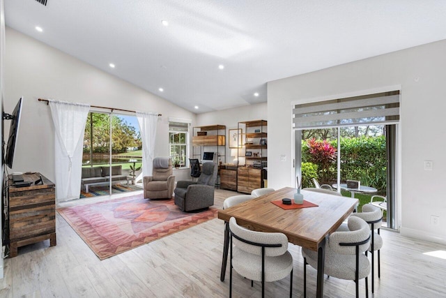 dining room with a wealth of natural light, vaulted ceiling, and light wood-type flooring