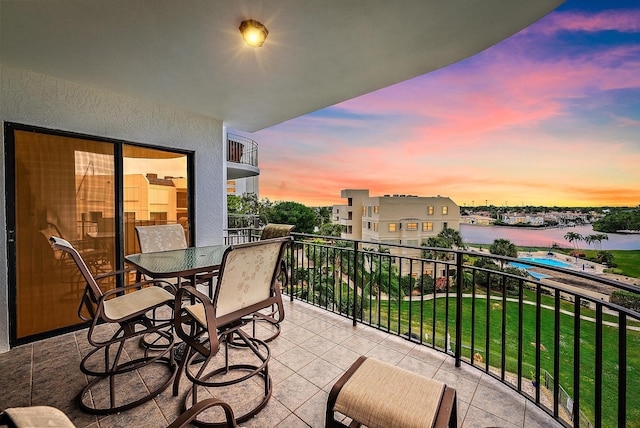 balcony at dusk featuring a water view