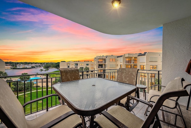 balcony at dusk featuring a water view