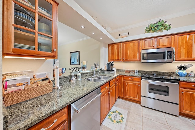 kitchen featuring sink, stainless steel appliances, dark stone countertops, crown molding, and light tile patterned floors