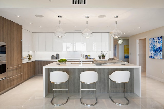 kitchen with white cabinets, a kitchen breakfast bar, sink, and decorative light fixtures