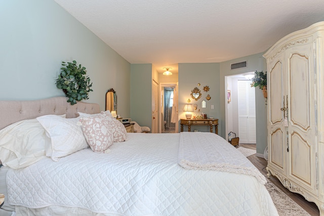 bedroom featuring a closet, light hardwood / wood-style floors, and a textured ceiling